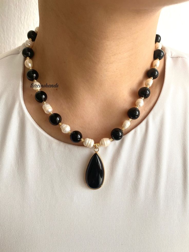 ✨Gold-Plated Black Agate and Freshwater Pearl Necklace | Black and White Elegant Necklace Enhance your jewelry collection with this stunning **Gold-Plated Necklace featuring the timeless contrast of **Black Agate** and **Freshwater Pearls**. This handcrafted necklace is a perfect accessory for both casual and formal occasions, adding a touch of elegance and sophistication to your style. ✨ **High-Quality Materials Made with durable gold-plated chains, this necklace combines the sleek look of **Black Agate** with the classic beauty of **Freshwater Pearls**. The gold plating ensures long-lasting shine and a luxurious appearance. 🖤 **Centerpiece The necklace is completed with a **Black Agate Pendant adding a bold and modern touch to the overall design. The agate's natural beauty complements t Black Beaded Necklaces With Pearl Pendant, Black Beaded Necklace With Pearl Pendant, Elegant Black Agate Beaded Necklace, Elegant Black Pendant Pearl Necklace, Black Crystal Necklace With Natural Stones, Black Teardrop Necklace With Natural Stones, Elegant Onyx Crystal Necklaces With Natural Stones, Black Agate Beaded Necklace With Natural Stones, Black Agate Necklace With Black Beads