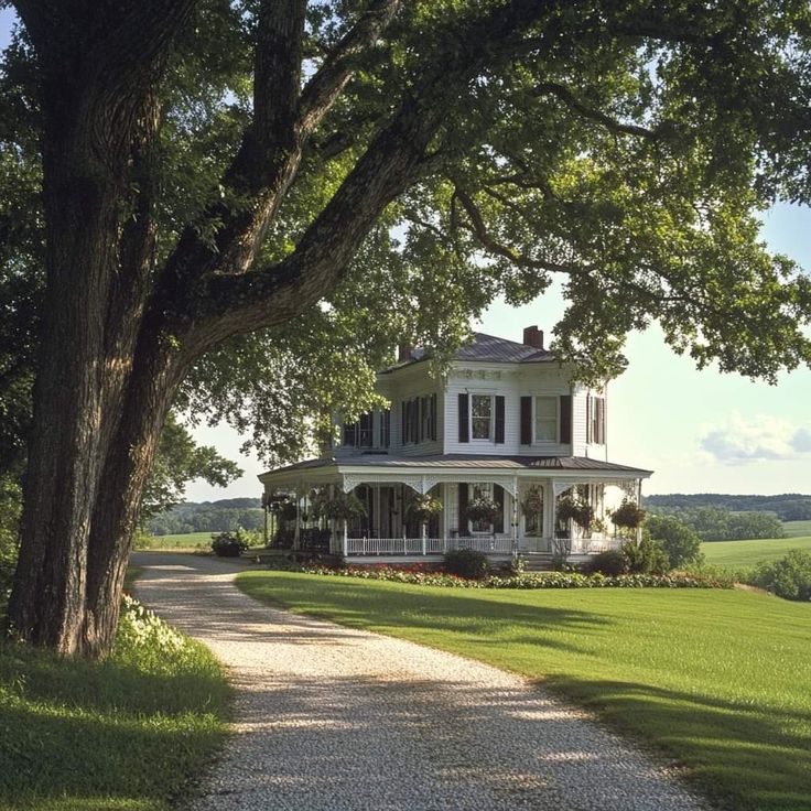 a large white house sitting on the side of a lush green field next to a tree