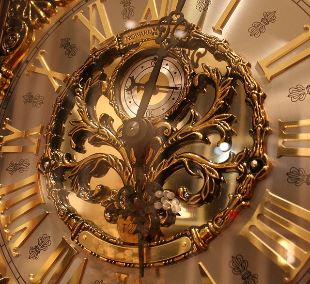 a close up view of a gold clock with roman numerals