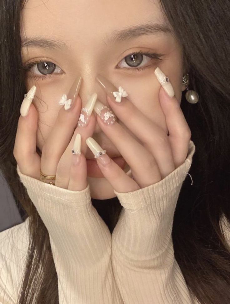 a woman holding her hands to her face with white nail art on it's nails