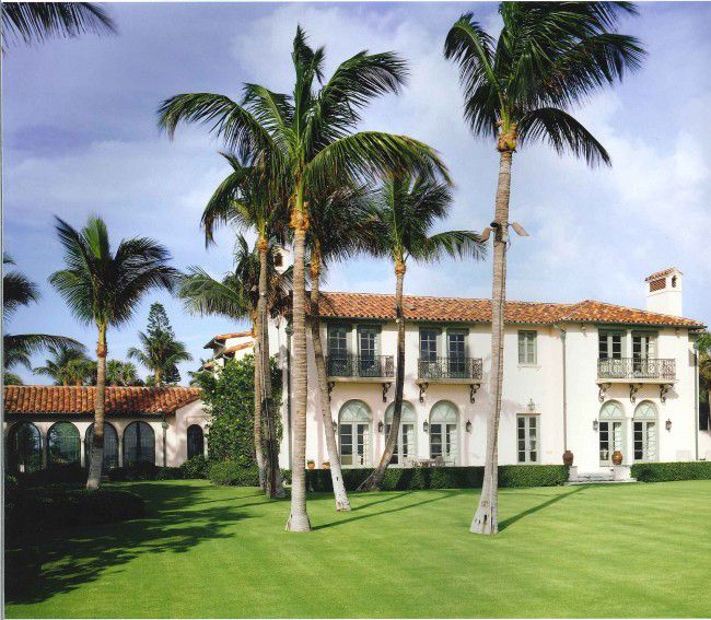 a large white house surrounded by palm trees