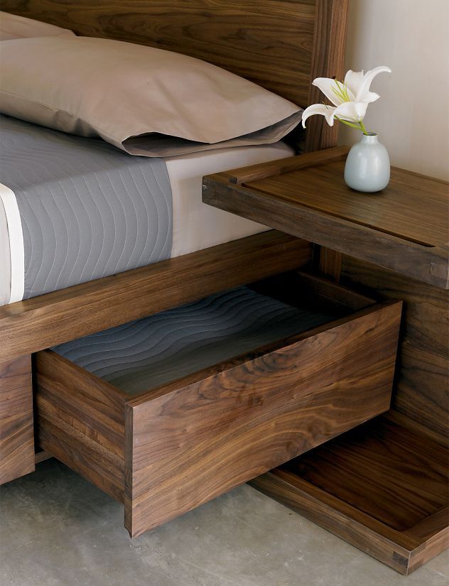 a bed with a wooden headboard and night stand next to a small end table