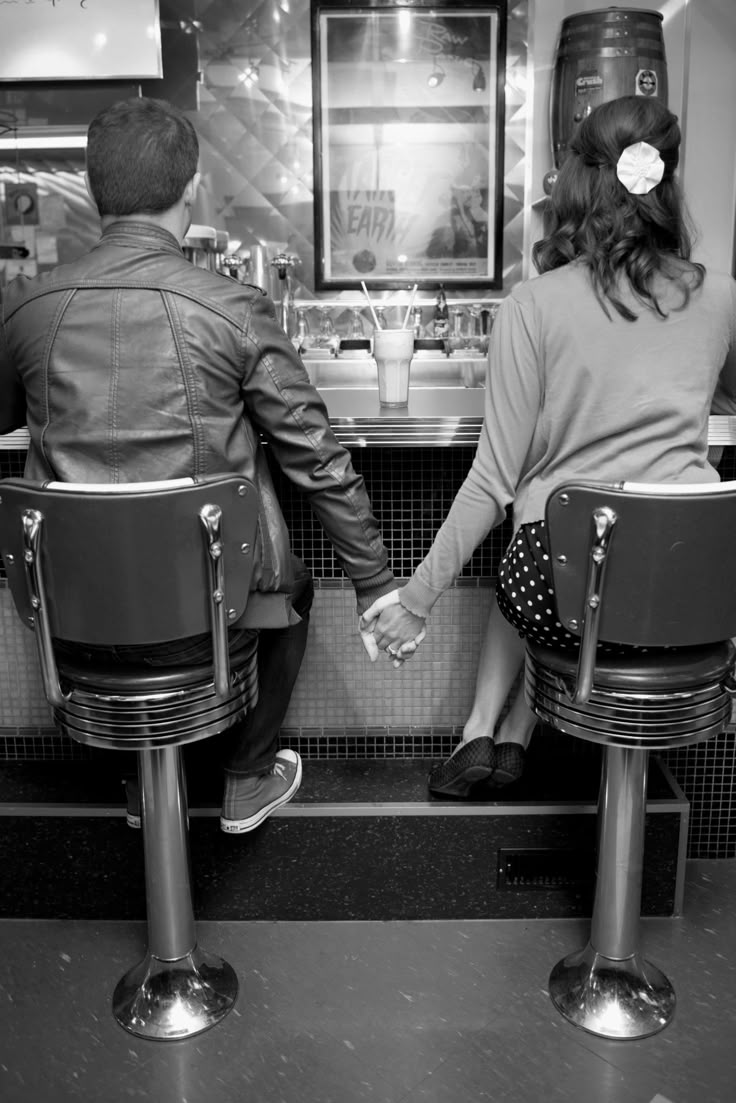 two people sitting at a bar with their backs to each other