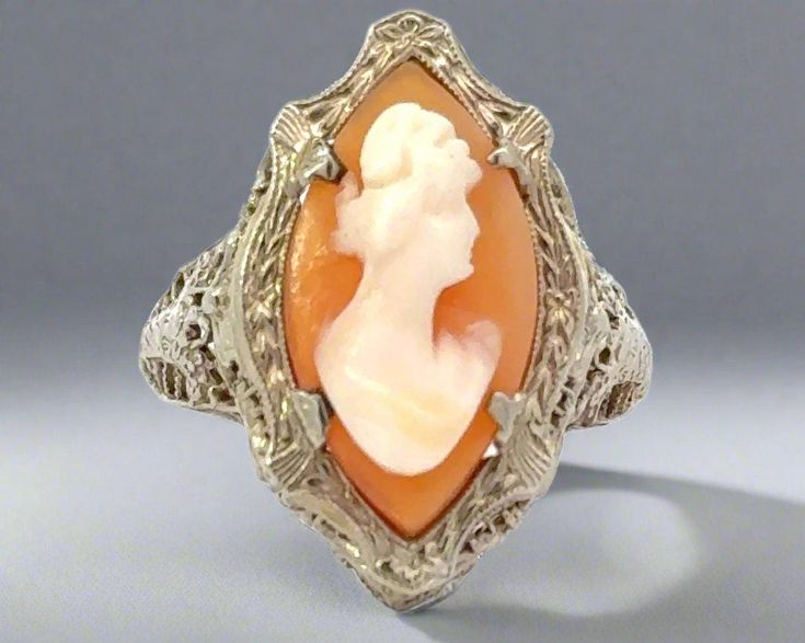 This antique 14K white gold ring boasts exceptional filigree work, a testament to craftsmanship of the past. Own a piece of history and add a touch of elegance to your wardrobe with this timeless piece. Crafted with care, this ring is a must-have for any jewelry collection. Jewelry Style : Ring Metal Type : 14K White Gold  Cameo : Agate and Hand Carved Shell Total Approximate Weight : 3.4 Grams Head of ring measurement : Approximately 25 mm x 15 mm Ring Size : 6.5 : Sizing may be done by your jeweler estate piece, sold as is, all weights are estimates Vintage Carved Jewelry For Anniversary, Carved Vintage Jewelry For Anniversary, Antique Engraved Wedding Ring With Carved Details, Antique Carved Engraved Wedding Ring, Heirloom Carved Engraved Ring For Collectors, Classic Filigree Ring With 17 Jewels For Wedding, Vintage Hallmarked Jewelry In 14k White Gold, Vintage Hallmarked 14k White Gold Jewelry, Hallmarked Vintage 14k White Gold Jewelry