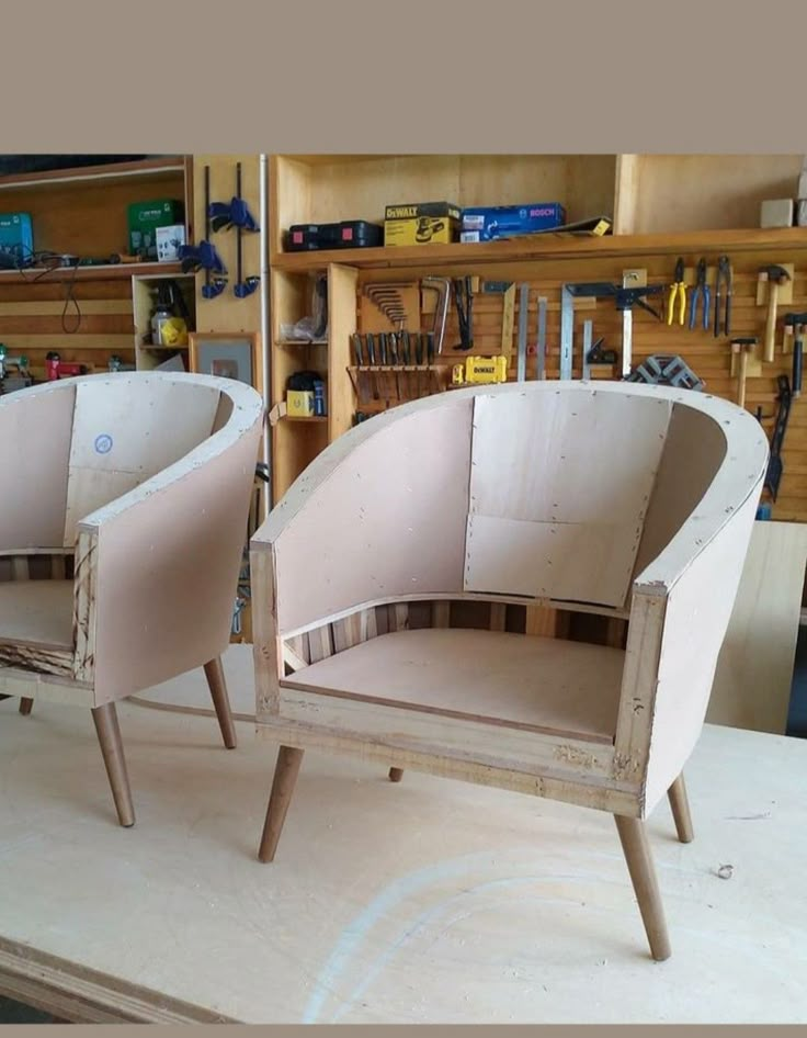 two wooden chairs sitting on top of a table next to a shelf filled with tools