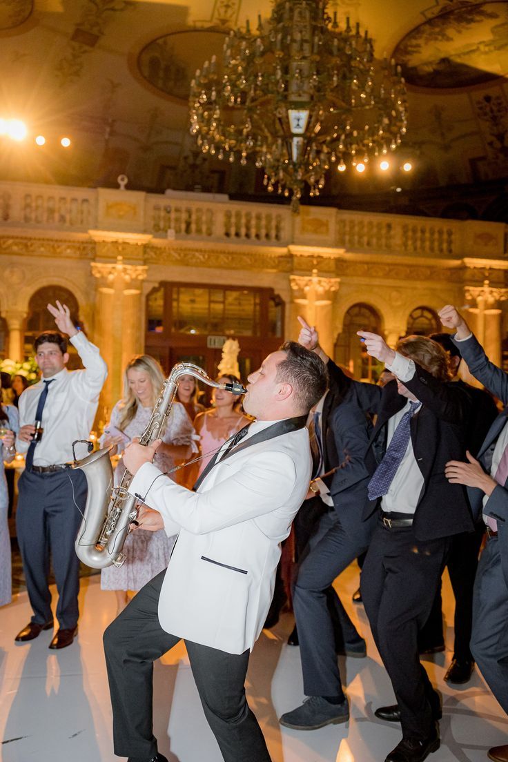 a group of people that are standing in the middle of a dance floor with one man holding a saxophone