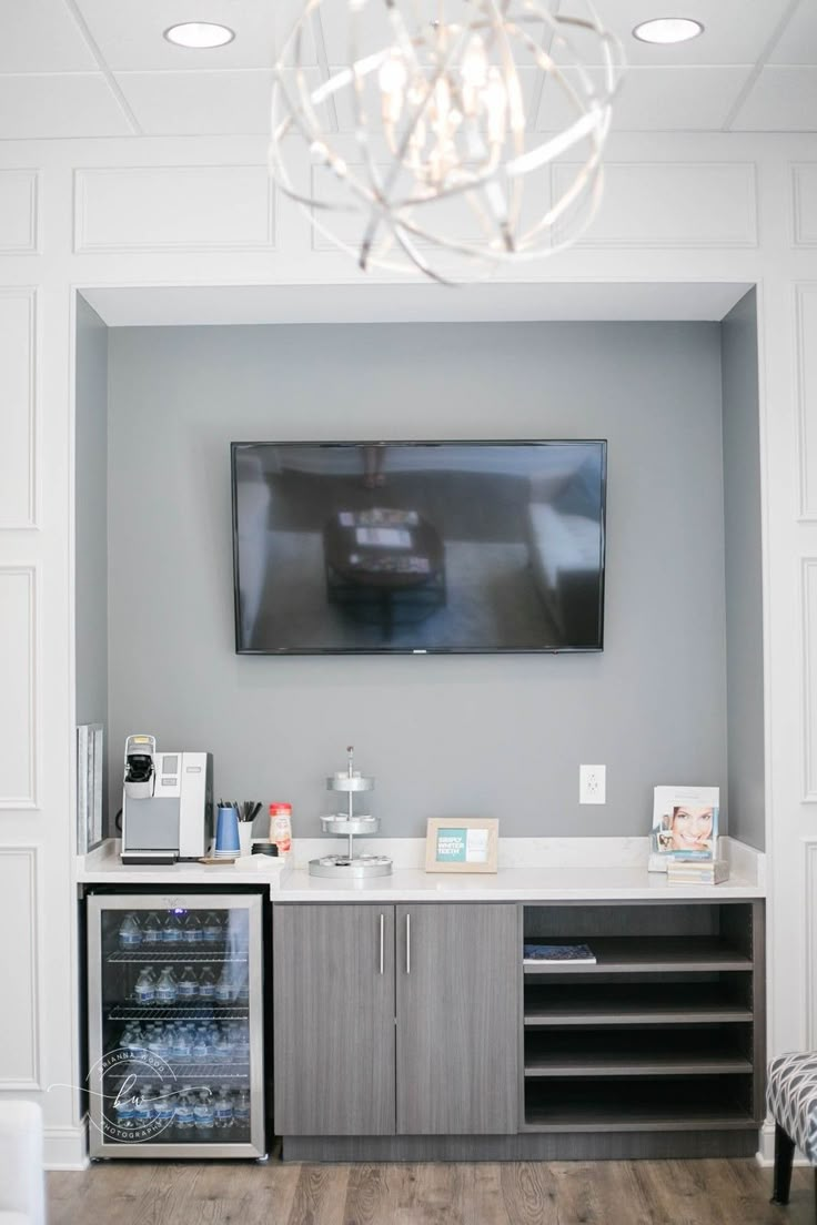 a television mounted on the wall above a bar in a room with wood flooring