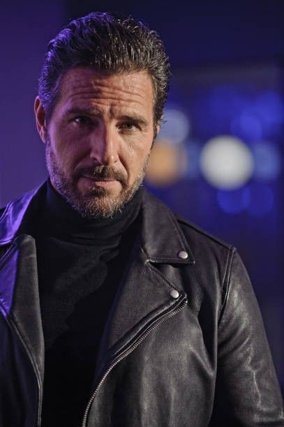 a man wearing a black leather jacket looking at the camera with a serious look on his face