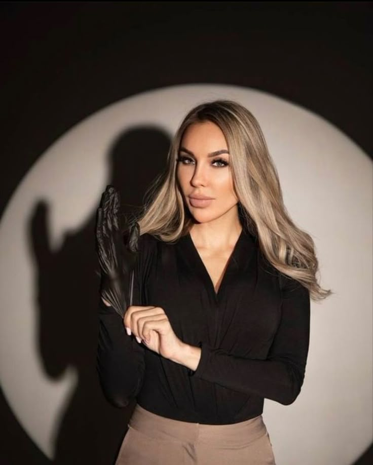 a woman with long blonde hair and black shirt holding a pair of scissors in her hands