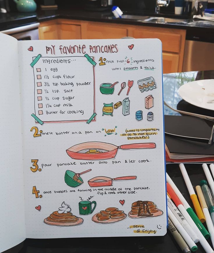 an open notebook with doodles on it in front of a kitchen counter and utensils