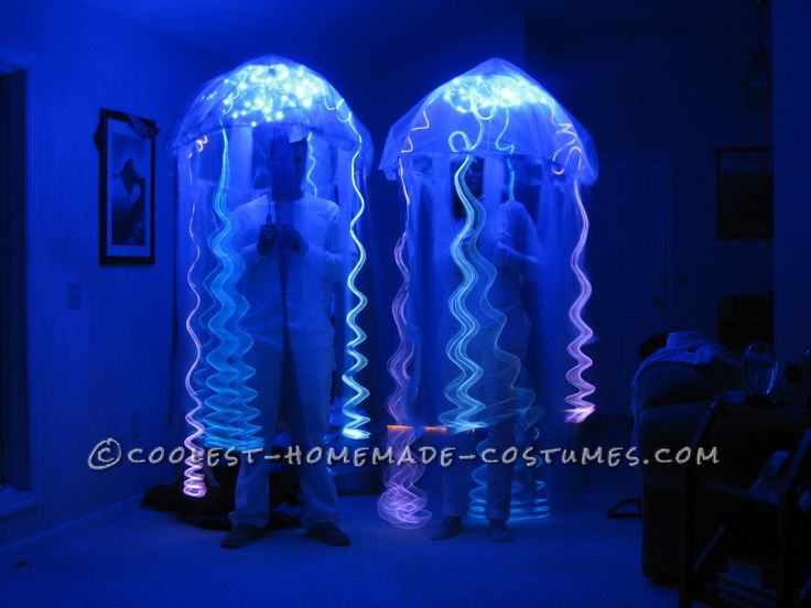 two people standing next to each other in front of some jellyfish shaped objects with blue lights on them