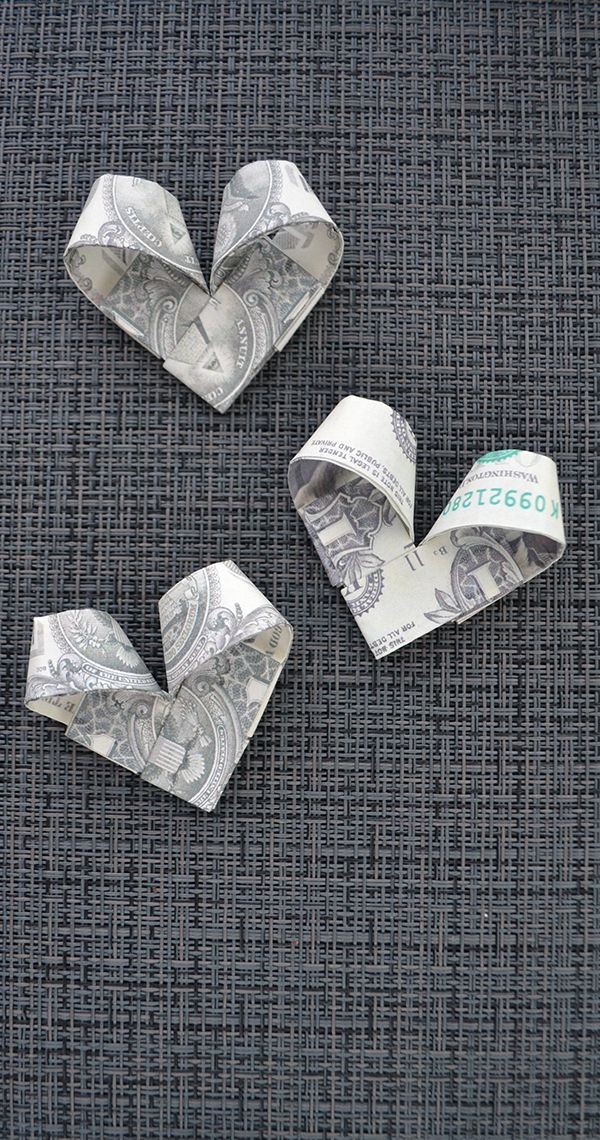 three origami hearts made out of dollar bills on a gray cloth with the word $ 500 written below them