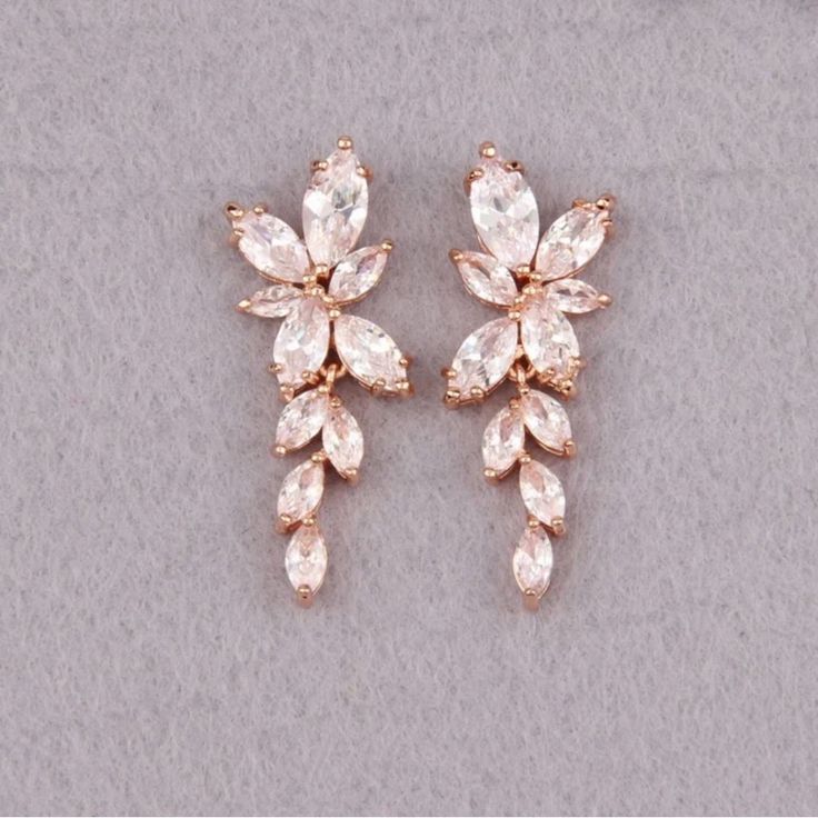 two pairs of gold tone earrings with clear stones on them, set against a gray background