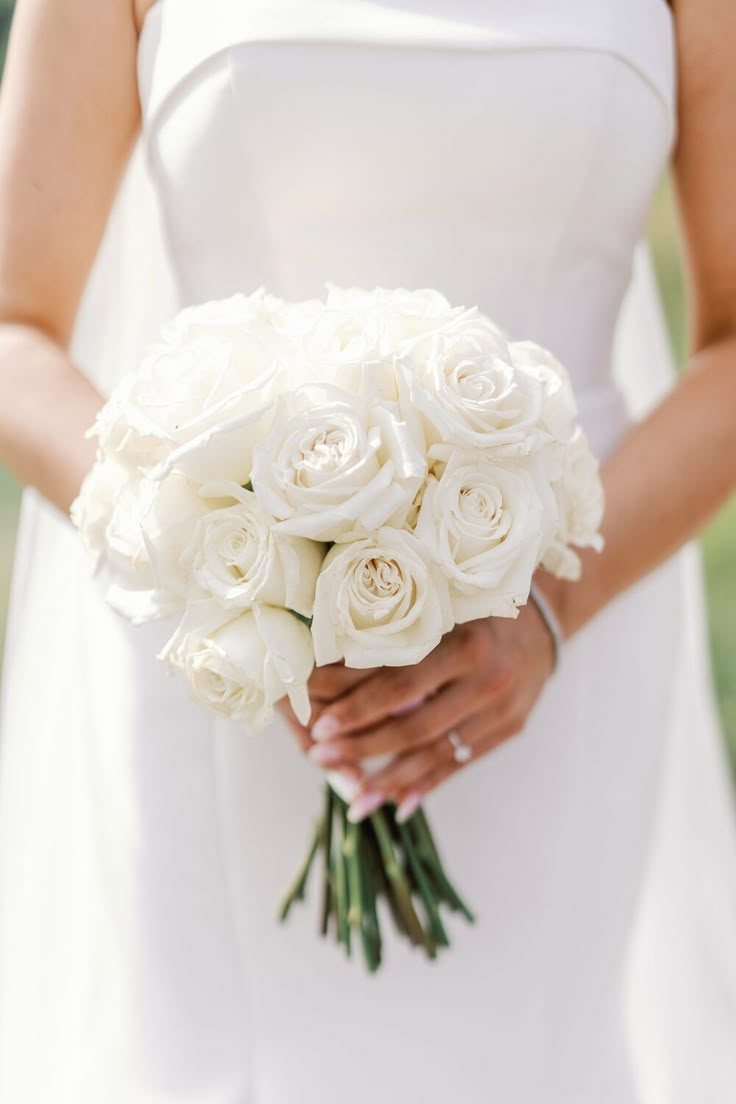 a bride holding a bouquet of white roses