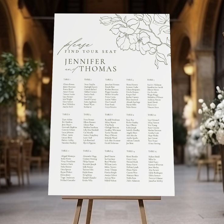 a sign with seating cards on it in front of a room filled with chairs and flowers