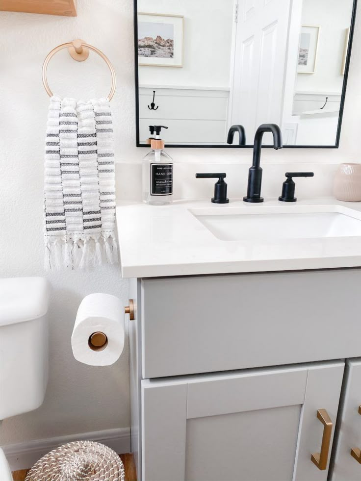 a bathroom with a sink, mirror and toilet paper roll on the floor next to it