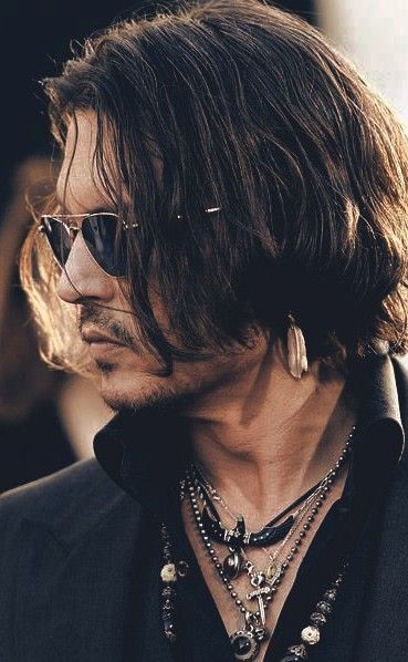 a man with long hair wearing sunglasses and a black shirt is looking off to the side