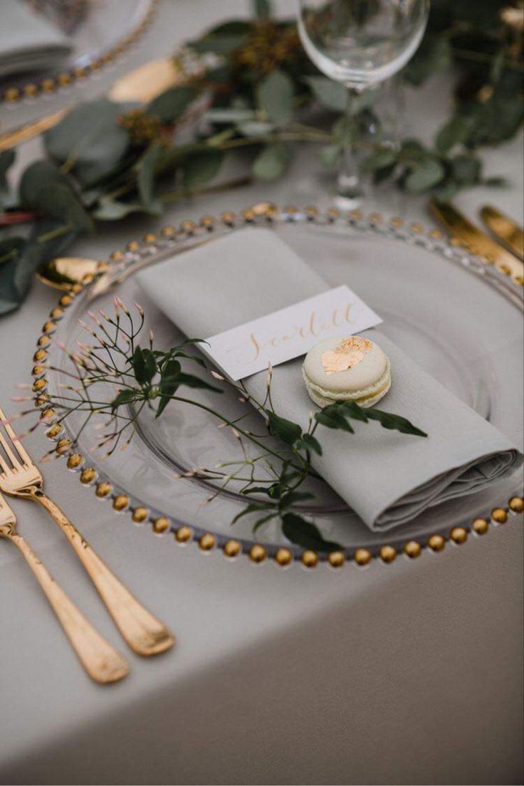 a place setting with silverware and greenery