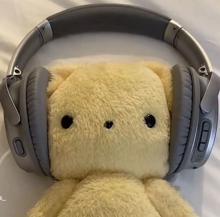 a teddy bear wearing headphones on top of a bed