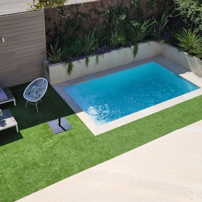 an above ground swimming pool with artificial grass around it and lounge chairs next to the pool