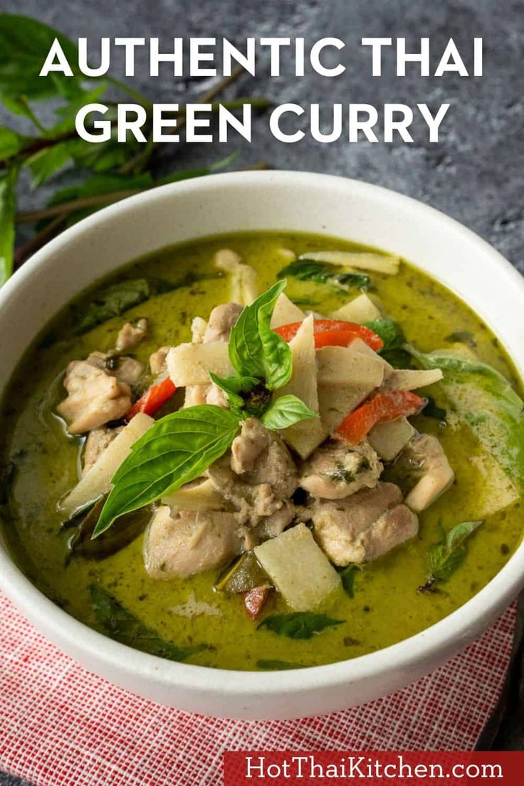 a white bowl filled with green curry next to a red and white checkered napkin