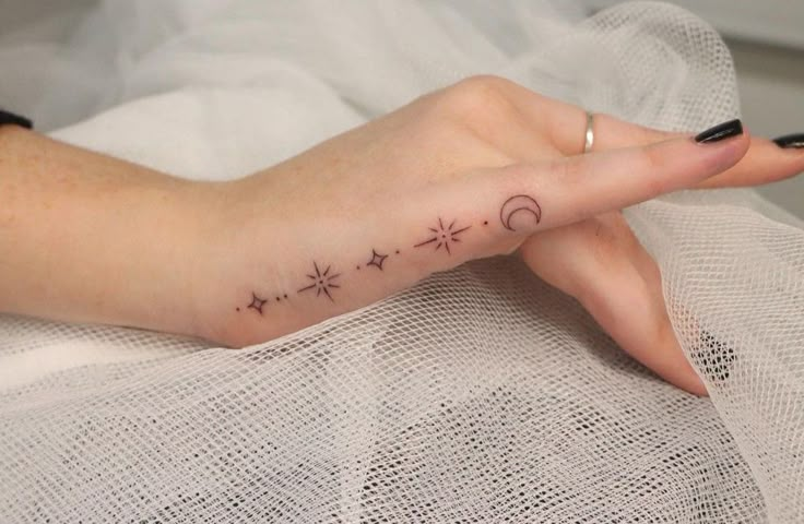 a woman's hand with a small star and moon tattoo on it