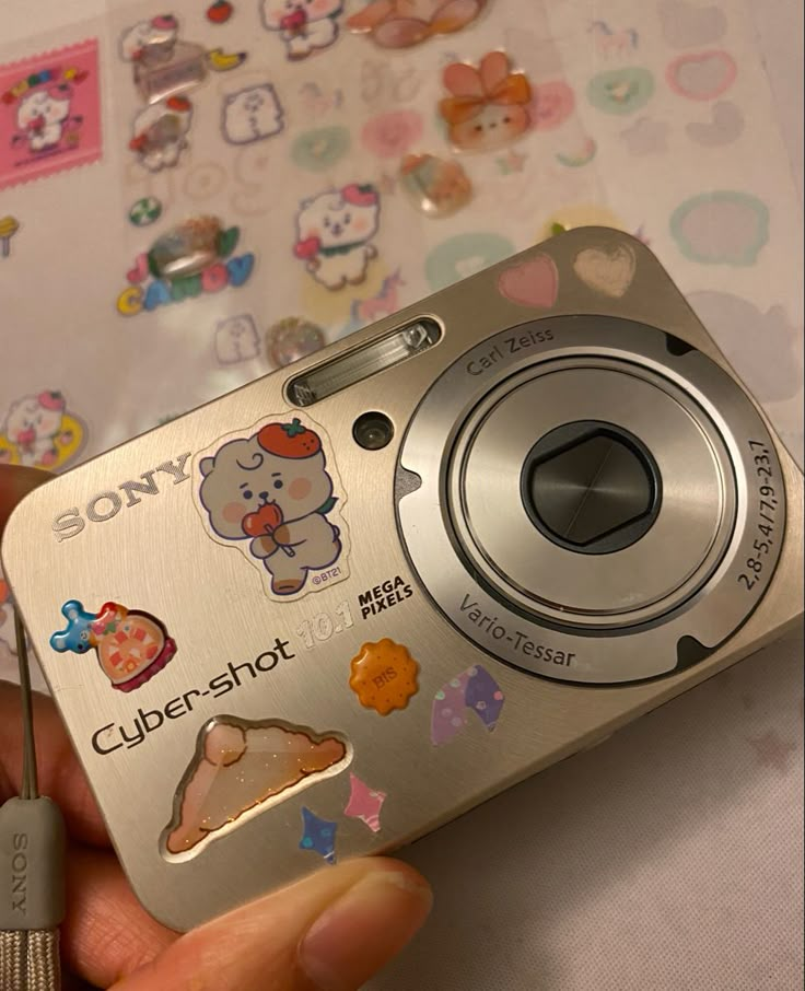 a person holding a camera with stickers on it