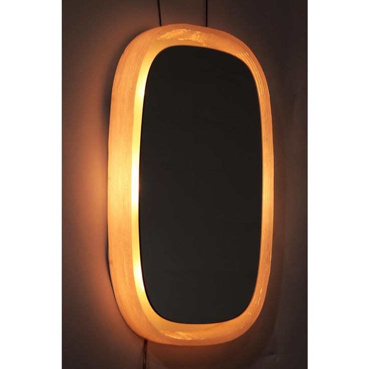 an oval shaped mirror is lit up by a light bulb on the side of it