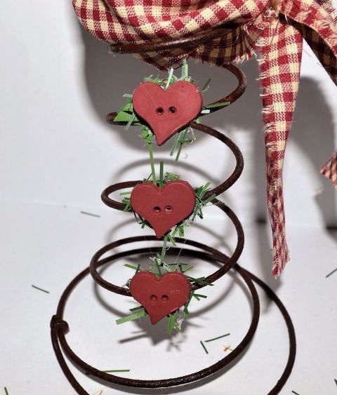 a red and white checkered bow on top of a metal spiral with hearts attached to it