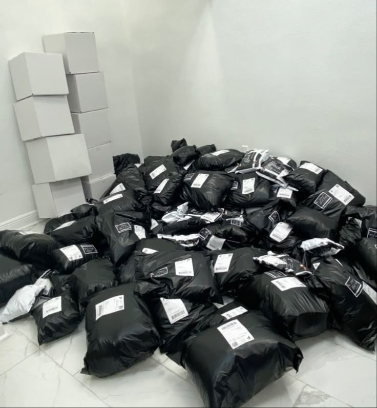 a pile of black bags sitting on top of a floor next to a white wall