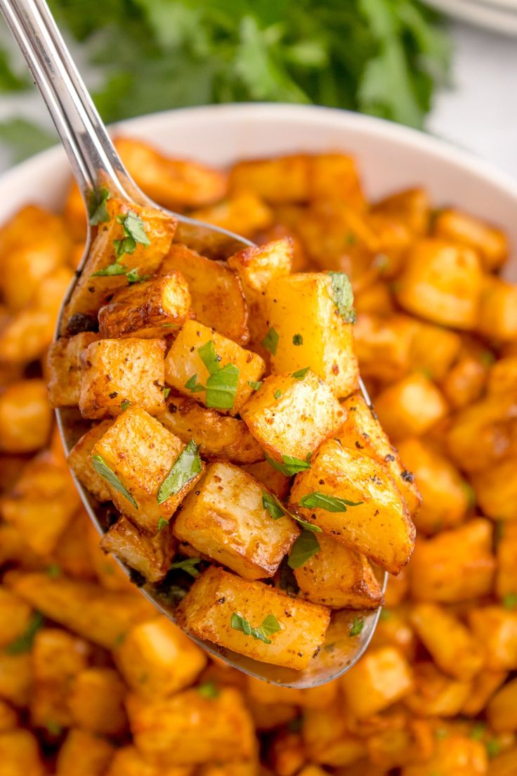 a close up of a spoon full of food with some parsley on top of it