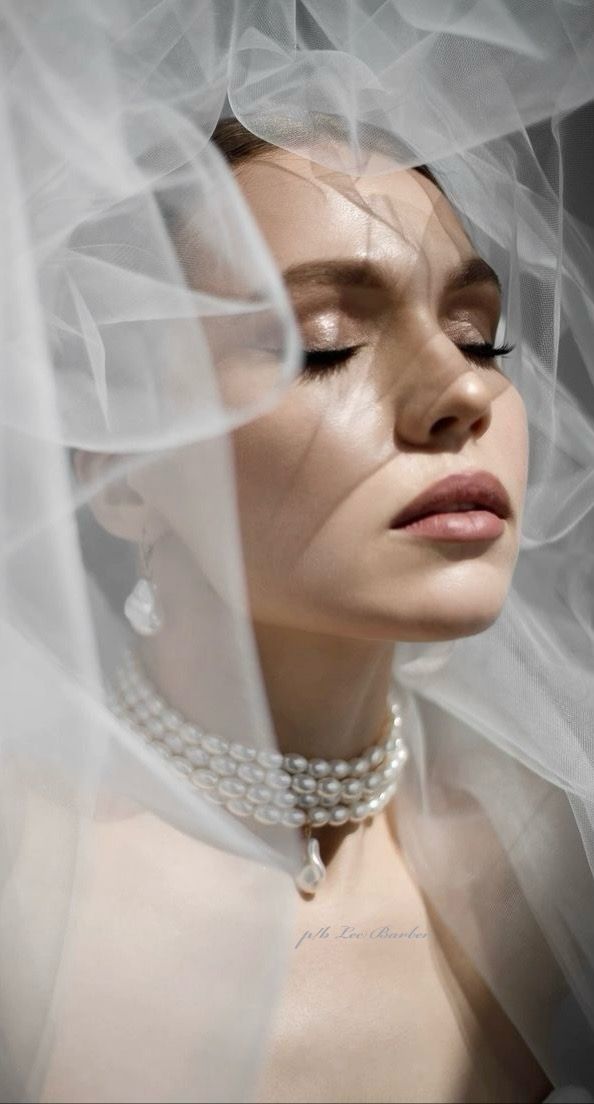 a woman wearing a veil and pearls necklace