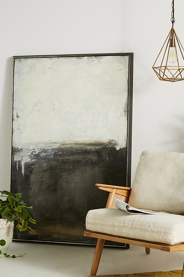 a chair sitting in front of a painting on the wall next to a potted plant