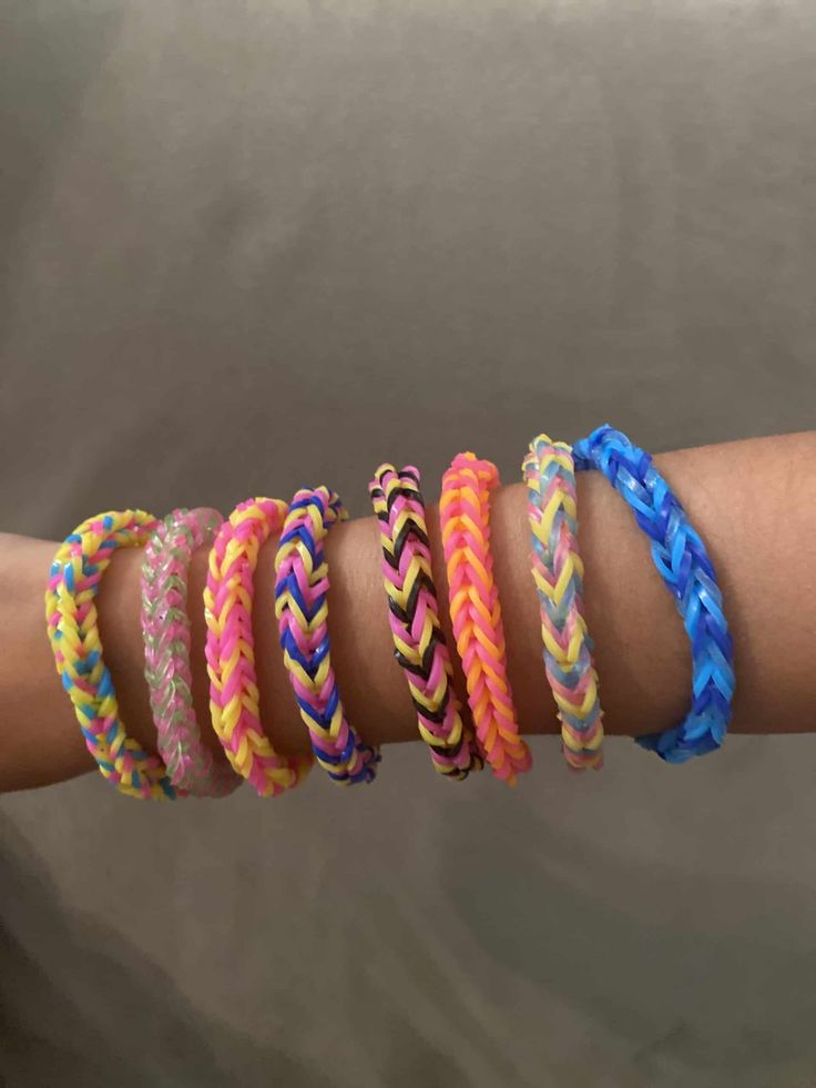 five different colored bracelets on someone's arm with one being held in the other hand