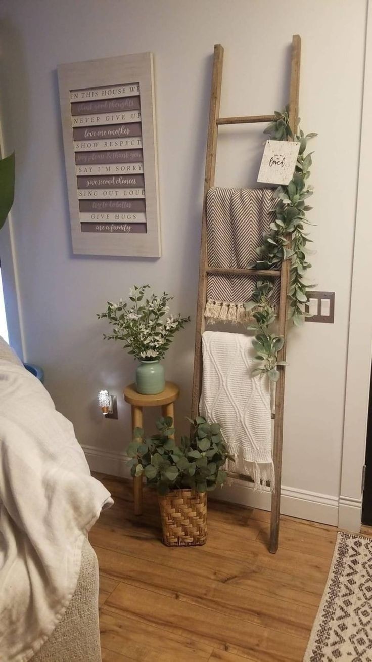 a room with a ladder, potted plants and towels on the shelf next to it