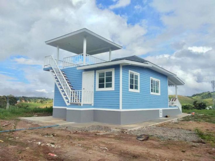 a blue and white house sitting on top of a dirt field