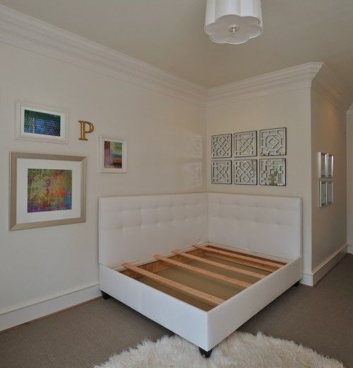 a white bed sitting in a bedroom next to a wall with pictures hanging on it