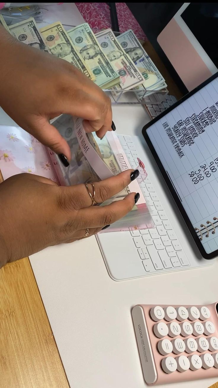 a person using a calculator on top of a laptop computer next to stacks of money