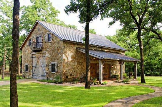 an old stone house in the middle of a grassy area with trees and grass around it