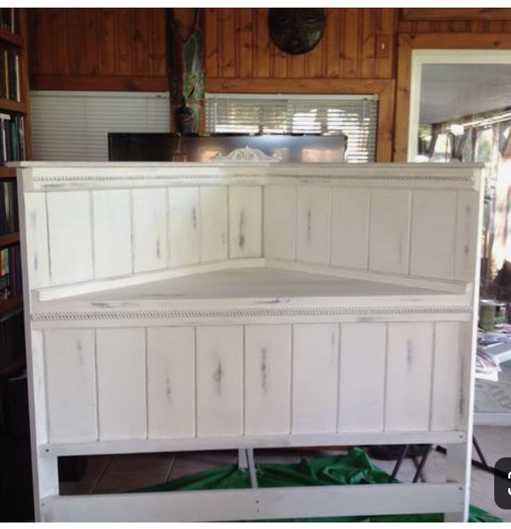 a white bed frame sitting in the middle of a room next to a bookshelf