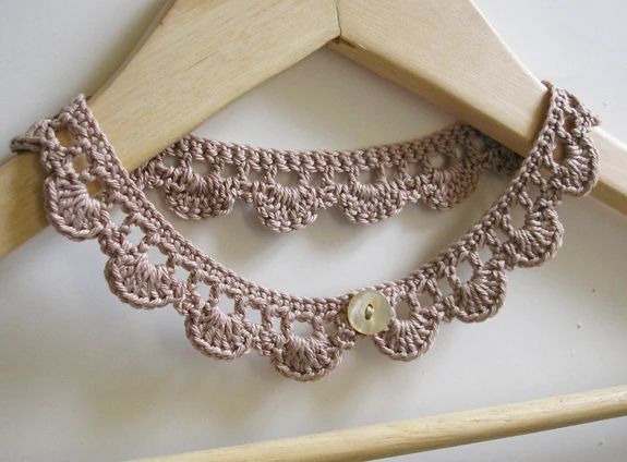 a crocheted necklace is hanging on a wooden hanger