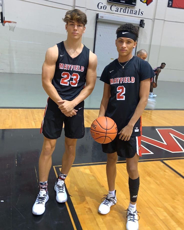 two young men standing next to each other on a court with basketballs in hand