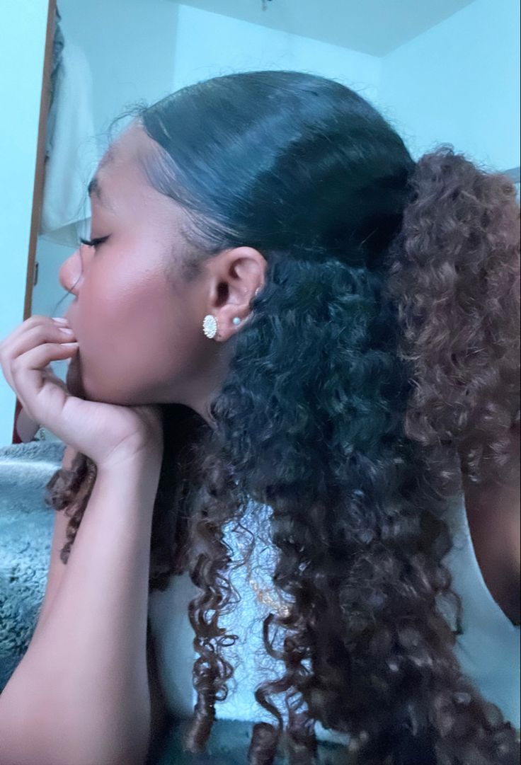 a woman with long curly hair sitting in front of a mirror looking at her reflection