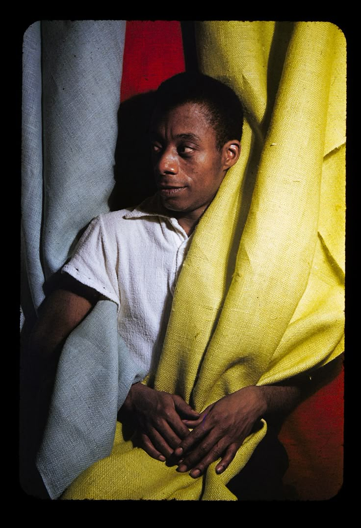 a man is wrapped up in a yellow blanket and posing for the camera with his hands on his chest