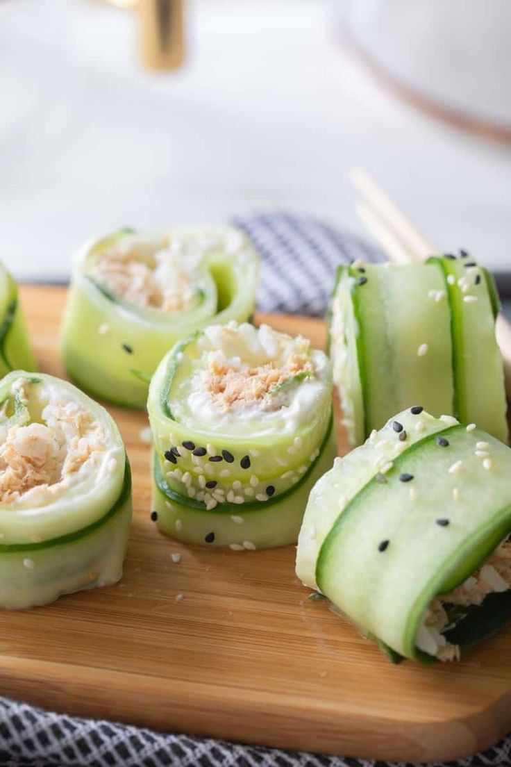 cucumber rolls with tuna and sesame seeds on a wooden cutting board, ready to be eaten