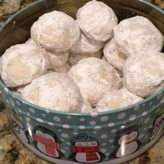 a bowl filled with snowball cookies on top of a counter