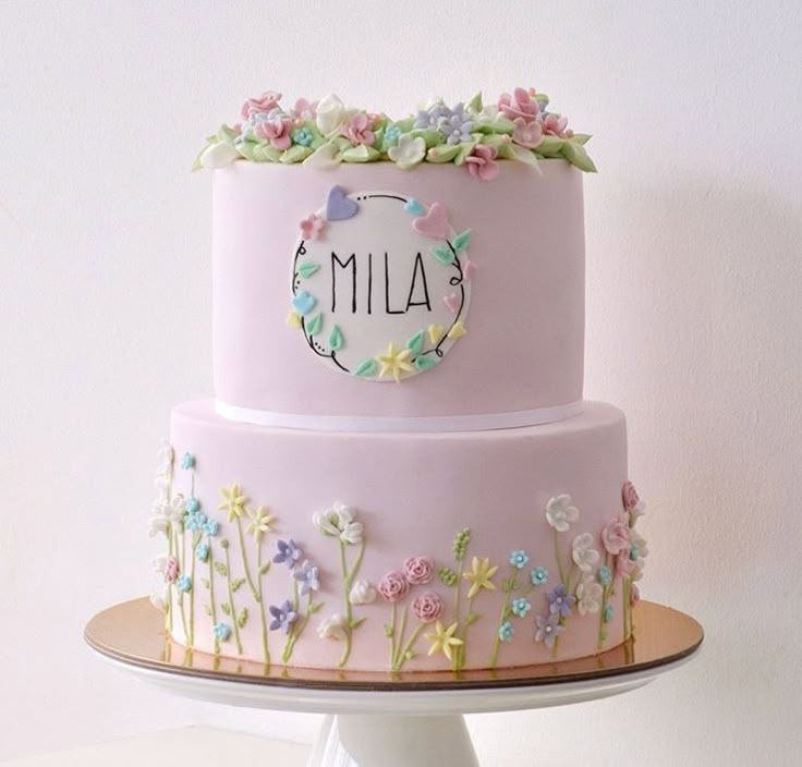 a three tiered cake decorated with flowers and the word mia on it's side