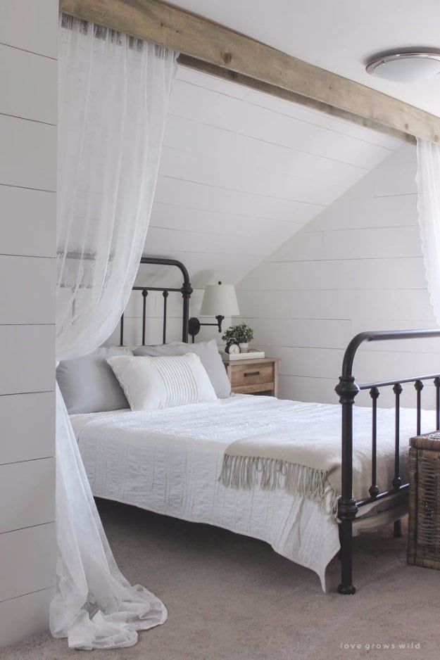 a white bed sitting under a window in a bedroom