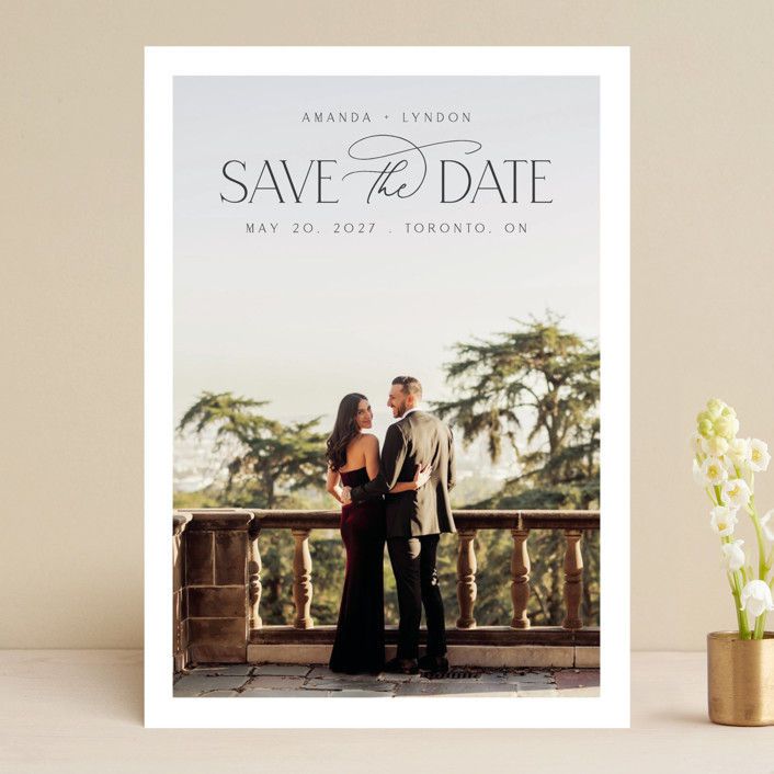 the save the date photo card is displayed next to a vase with flowers