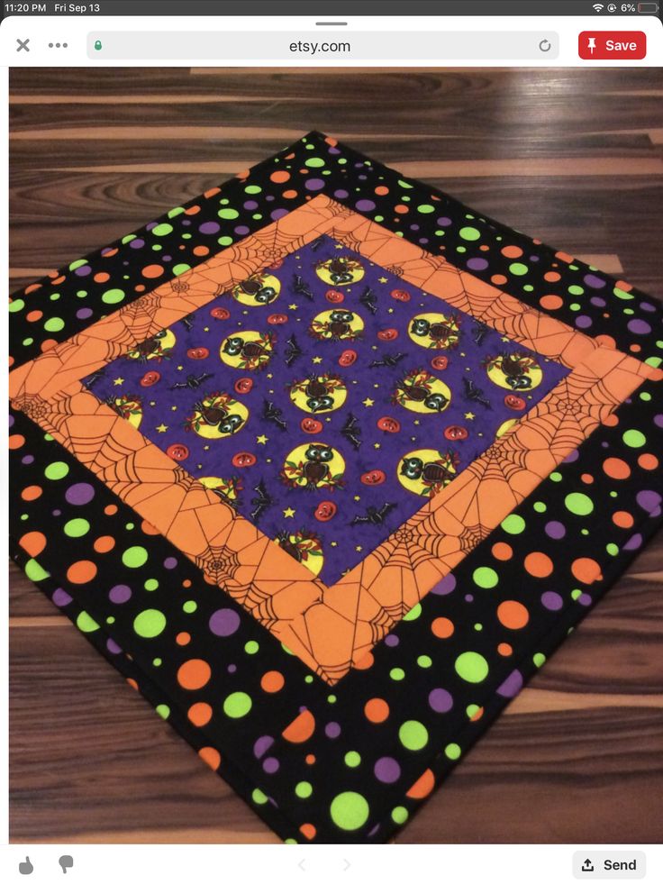 an orange and purple square with black polka dots on it, sitting on top of a wooden floor